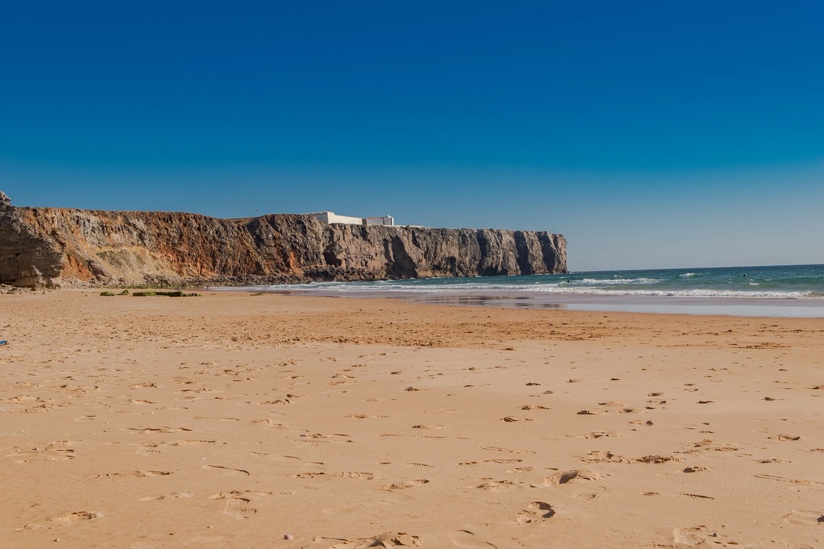 Golden sand beach beneath dramatic cliffs on the Algarve coast, Portugal